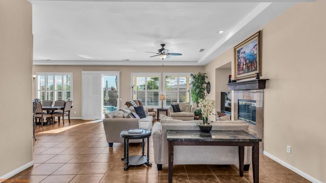 tiled living room featuring ceiling fan, a healthy amount of sunlight, and a fireplace