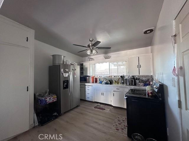 kitchen featuring white cabinetry, ceiling fan, stainless steel appliances, decorative backsplash, and light wood-type flooring