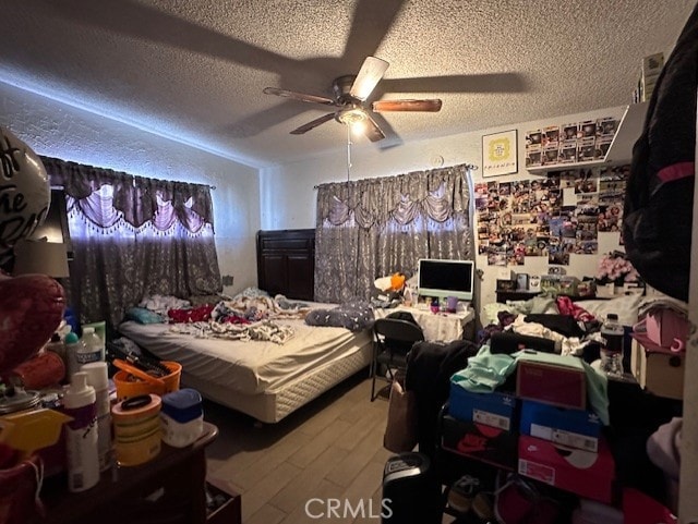 bedroom with ceiling fan, a textured ceiling, and hardwood / wood-style flooring