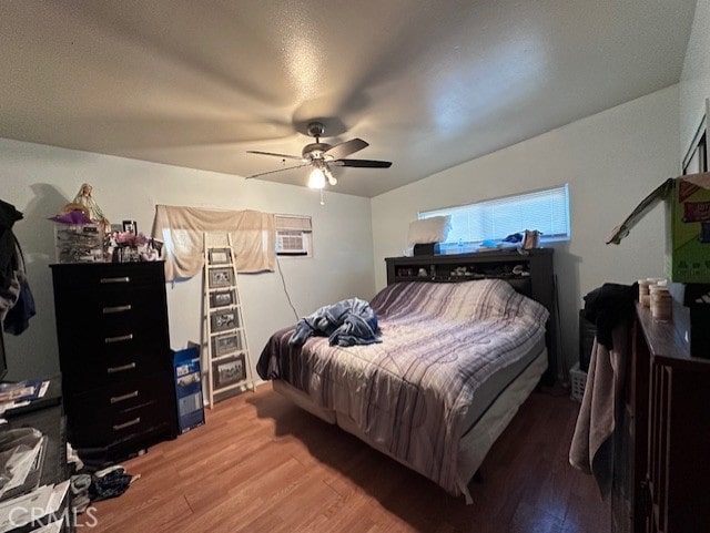 bedroom featuring ceiling fan, wood-type flooring, and a wall mounted air conditioner