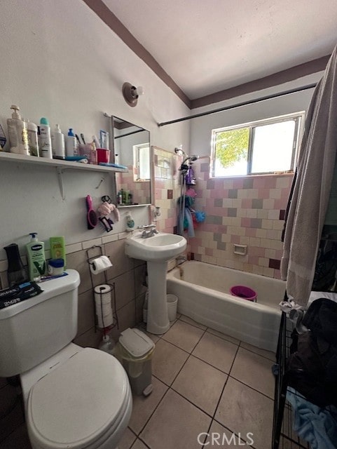 bathroom with tile patterned flooring, shower / bath combination with curtain, toilet, and tile walls