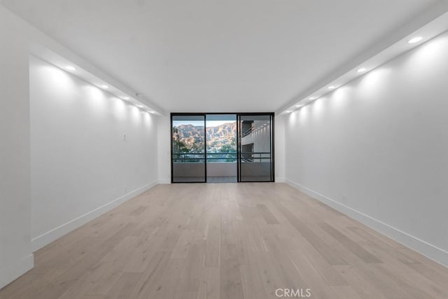 unfurnished room featuring light hardwood / wood-style floors and a wall of windows