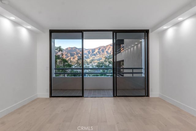 spare room with a mountain view and light wood-type flooring