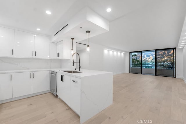 kitchen with pendant lighting, backsplash, expansive windows, sink, and white cabinetry