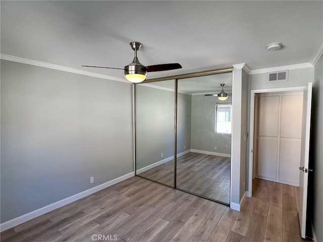 unfurnished bedroom featuring ceiling fan, a closet, ornamental molding, and light wood-type flooring