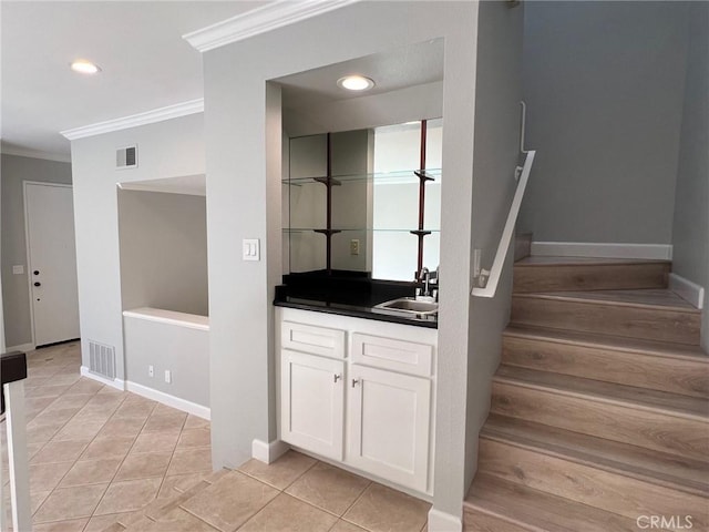 stairs with tile patterned floors, crown molding, and sink