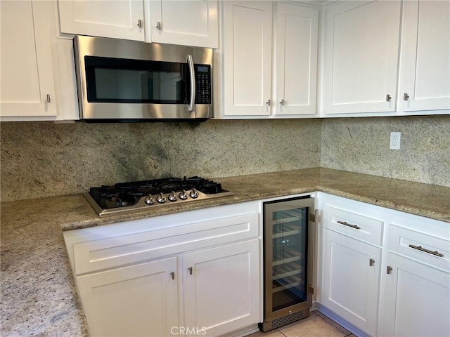 kitchen featuring white cabinets, appliances with stainless steel finishes, and beverage cooler