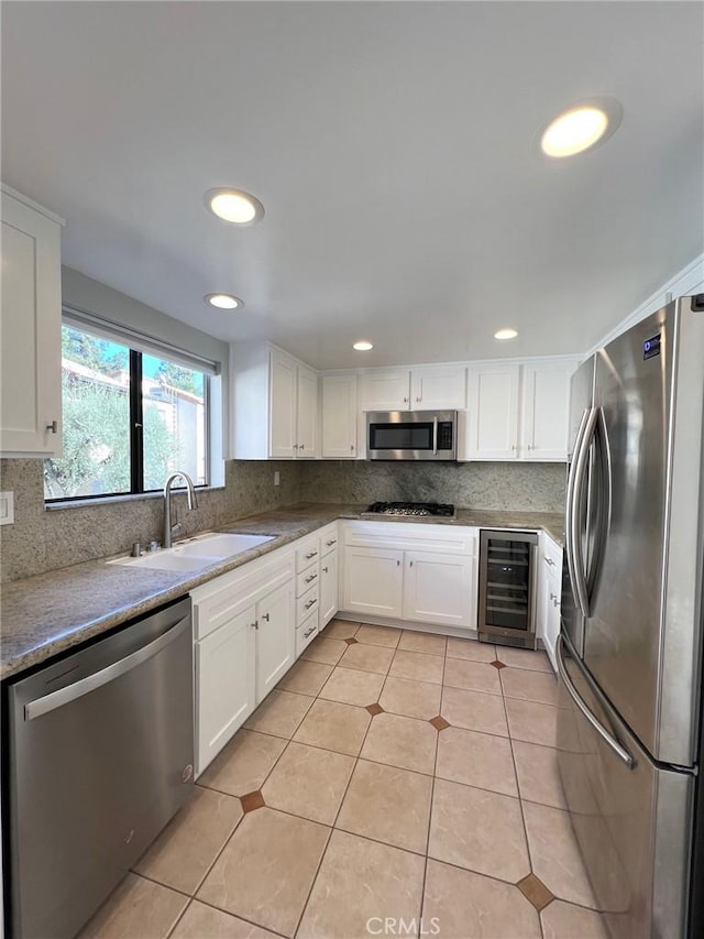 kitchen with sink, wine cooler, light tile patterned floors, white cabinetry, and stainless steel appliances