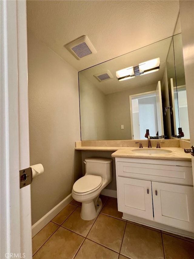 bathroom with tile patterned floors, vanity, a textured ceiling, and toilet