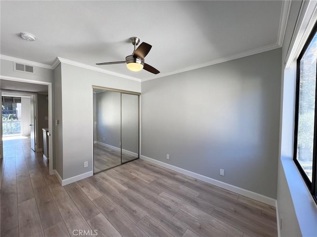 unfurnished bedroom featuring hardwood / wood-style floors, ceiling fan, crown molding, and a closet