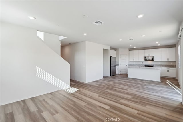 unfurnished living room featuring sink and light wood-type flooring