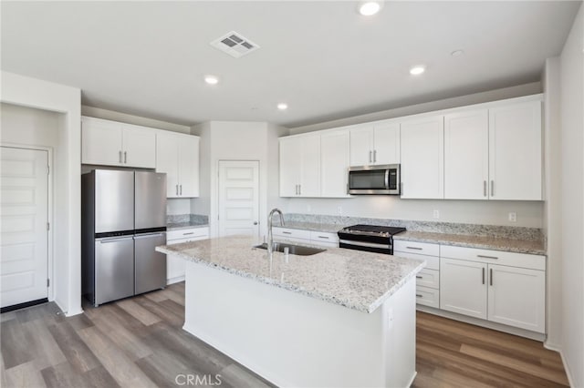 kitchen with stainless steel appliances, white cabinetry, sink, and a center island with sink