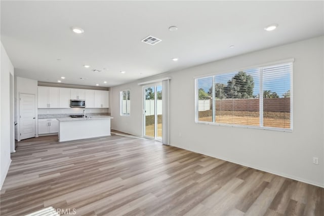 unfurnished living room featuring sink and light wood-type flooring