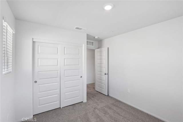 unfurnished bedroom with light carpet and a closet