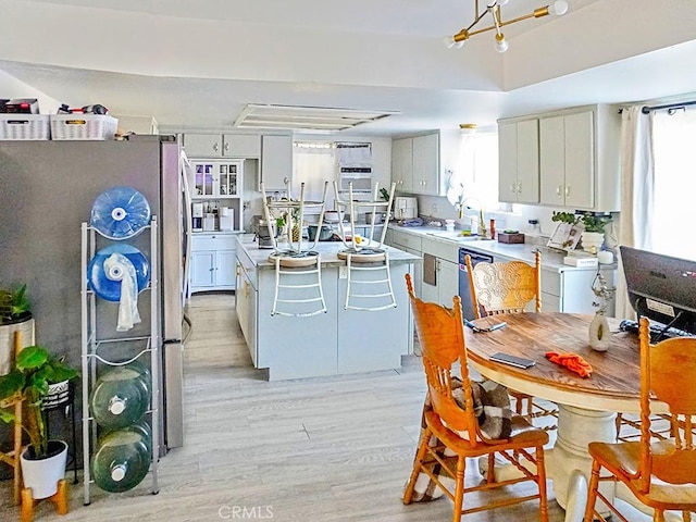 kitchen with white cabinetry, sink, light hardwood / wood-style flooring, a kitchen island, and appliances with stainless steel finishes