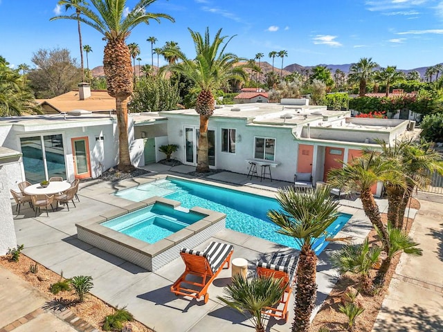 view of pool with a mountain view, a patio, and an in ground hot tub