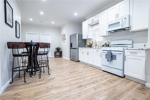 kitchen featuring white cabinets, light hardwood / wood-style floors, and white appliances