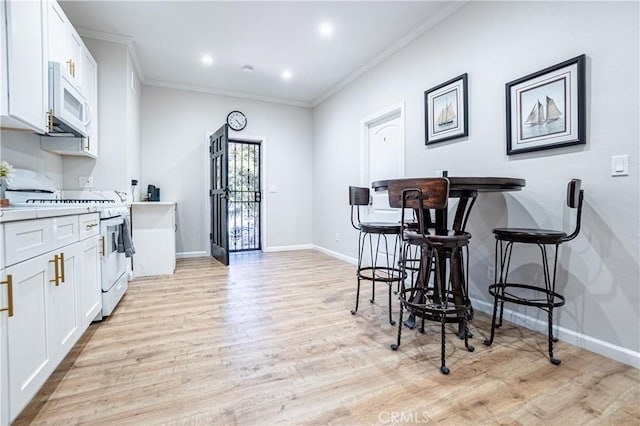 kitchen featuring stove, white cabinetry, light wood-type flooring, and ornamental molding