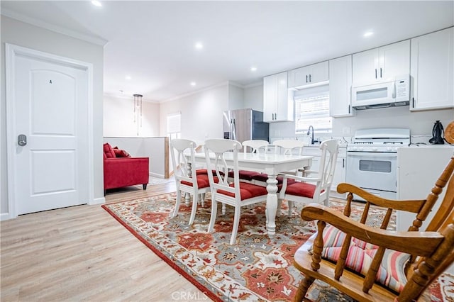 kitchen with pendant lighting, white appliances, light hardwood / wood-style flooring, ornamental molding, and white cabinetry