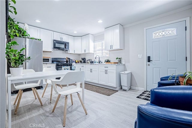 kitchen featuring ornamental molding, sink, black appliances, white cabinets, and light hardwood / wood-style floors