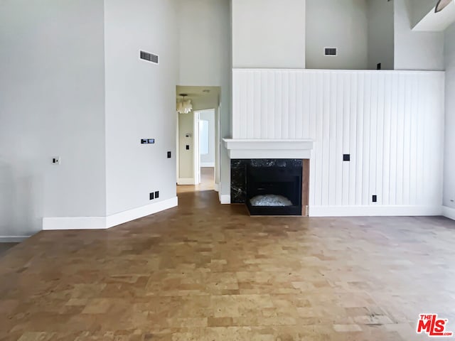 unfurnished living room with wood-type flooring, a towering ceiling, and a fireplace