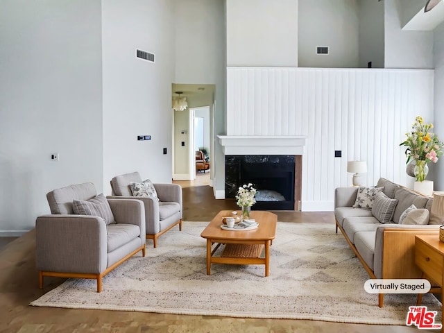 living room with a fireplace, a towering ceiling, and hardwood / wood-style flooring