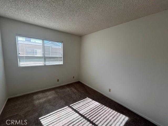 carpeted spare room featuring a textured ceiling