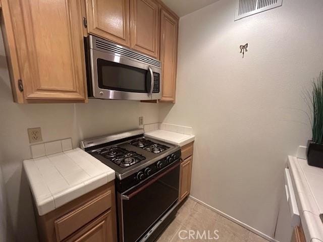 kitchen with black gas range oven and tile counters