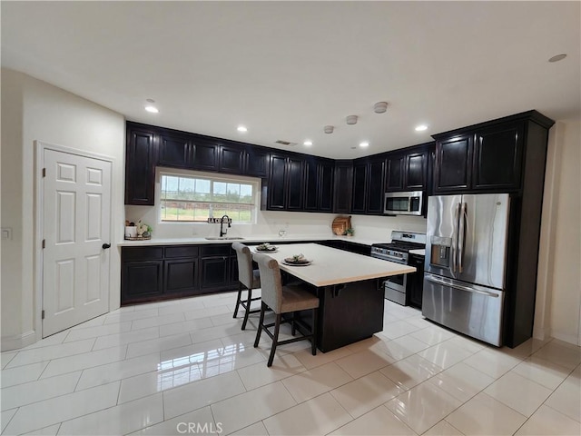 kitchen with stainless steel appliances, sink, a center island, light tile patterned flooring, and a kitchen breakfast bar