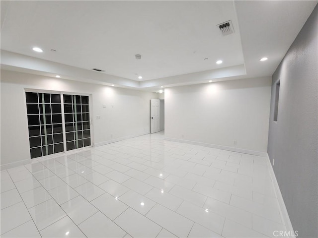 tiled spare room featuring a tray ceiling