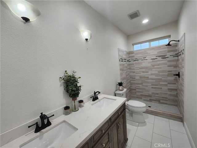 bathroom with tiled shower, tile patterned floors, vanity, and toilet