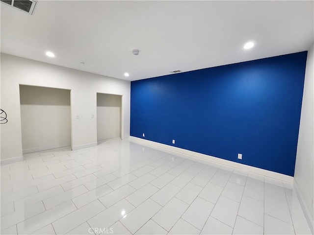 unfurnished room featuring baseboards, visible vents, and recessed lighting