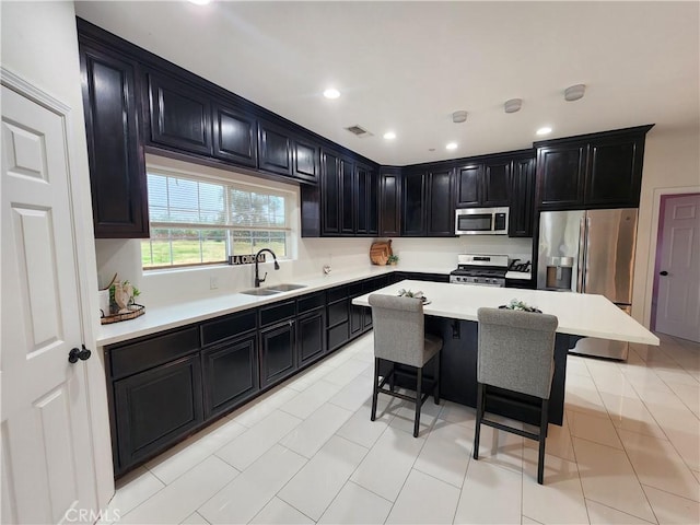 kitchen featuring a kitchen breakfast bar, stainless steel appliances, light tile patterned floors, a kitchen island, and sink