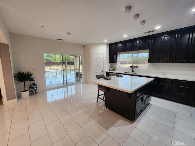 kitchen with sink, a breakfast bar, light tile patterned flooring, and a kitchen island