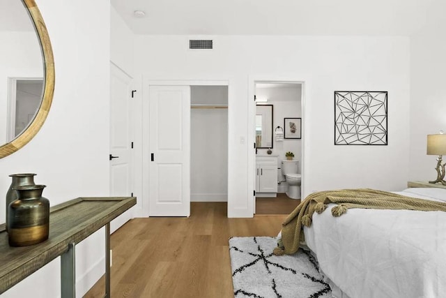 bedroom with a closet, ensuite bath, and light hardwood / wood-style flooring