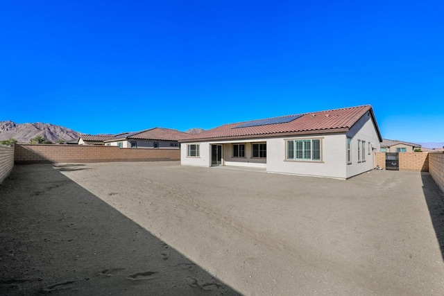 view of front facade featuring a patio, a mountain view, and solar panels