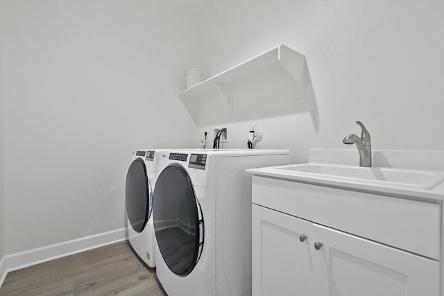 washroom with hardwood / wood-style flooring, washer and dryer, sink, and cabinets