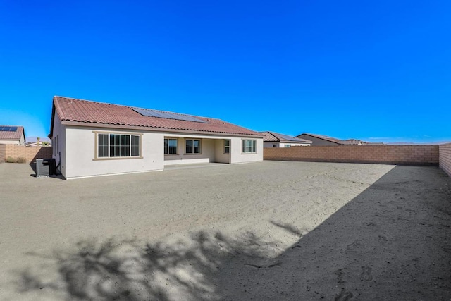 back of house featuring central AC unit and solar panels