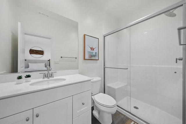 bathroom featuring vanity, hardwood / wood-style flooring, a shower with door, and toilet