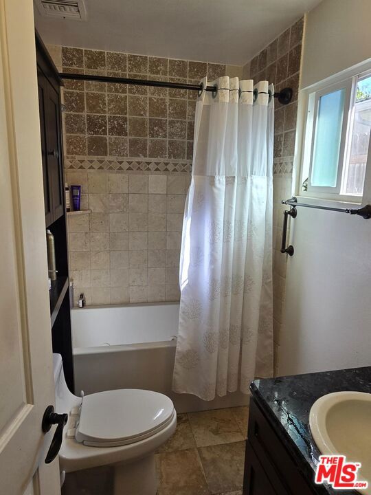 full bathroom with tile patterned flooring, vanity, shower / bath combo, and toilet