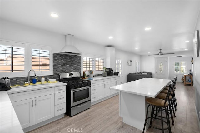 kitchen featuring stainless steel gas stove, light hardwood / wood-style flooring, white cabinetry, and custom exhaust hood