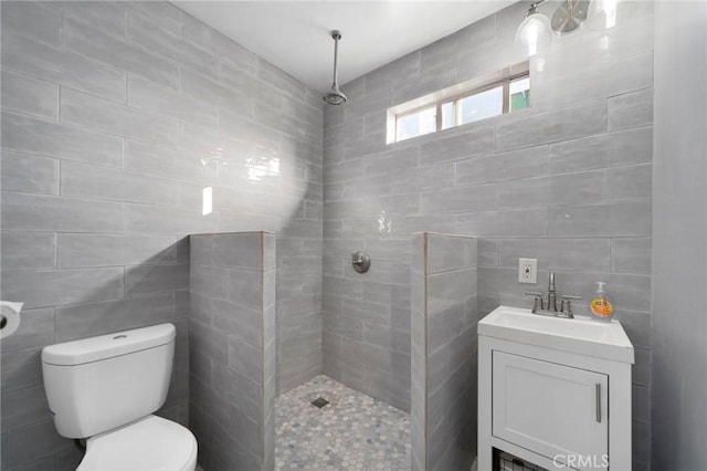 bathroom featuring toilet, vanity, tile walls, and walk in shower