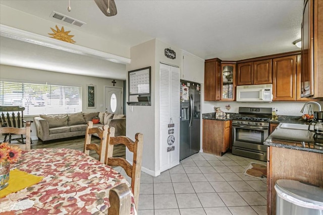 kitchen with ceiling fan, sink, stainless steel gas range oven, refrigerator with ice dispenser, and light tile patterned flooring