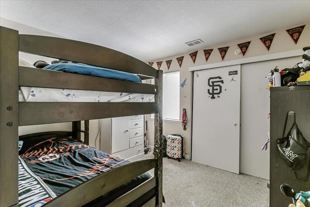 carpeted bedroom featuring a textured ceiling and a closet