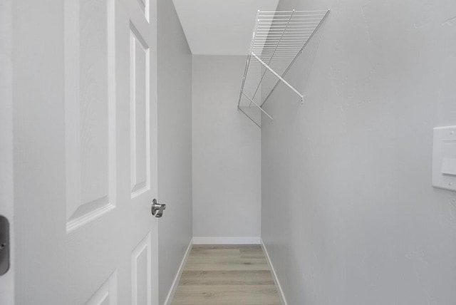 walk in closet with light hardwood / wood-style flooring