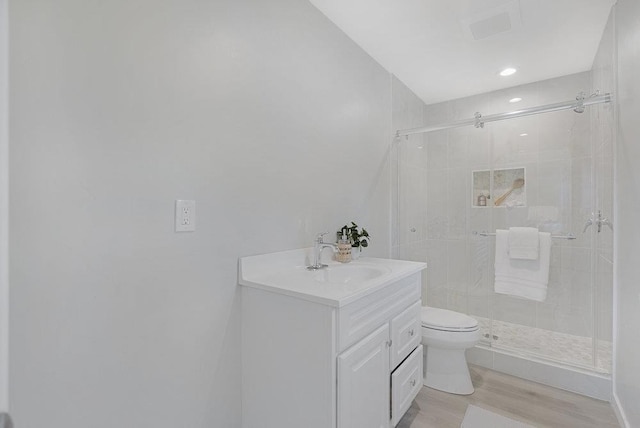 bathroom featuring hardwood / wood-style flooring, vanity, toilet, and a shower with door