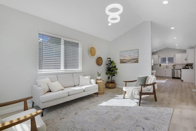 living room with vaulted ceiling, a chandelier, and light hardwood / wood-style floors