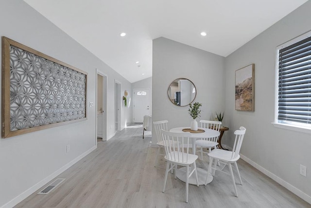 dining room with light hardwood / wood-style flooring and vaulted ceiling