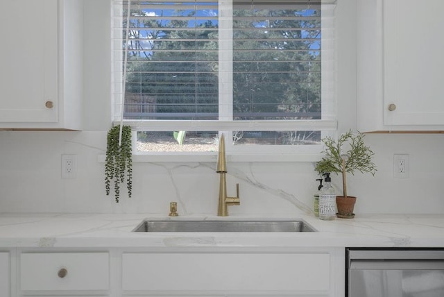 room details with light stone counters, sink, and white cabinets