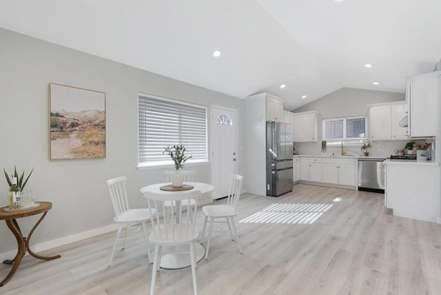 dining room featuring light hardwood / wood-style flooring, sink, and vaulted ceiling